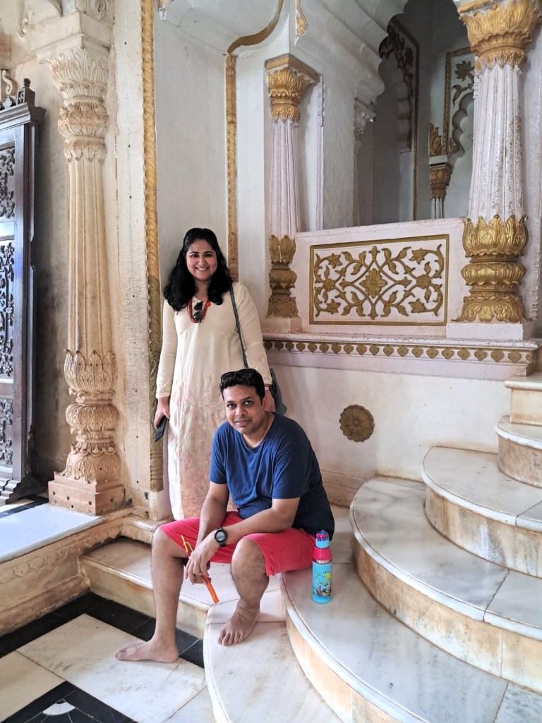 An Indian man & woman smile for the camera inside a cenotaph.